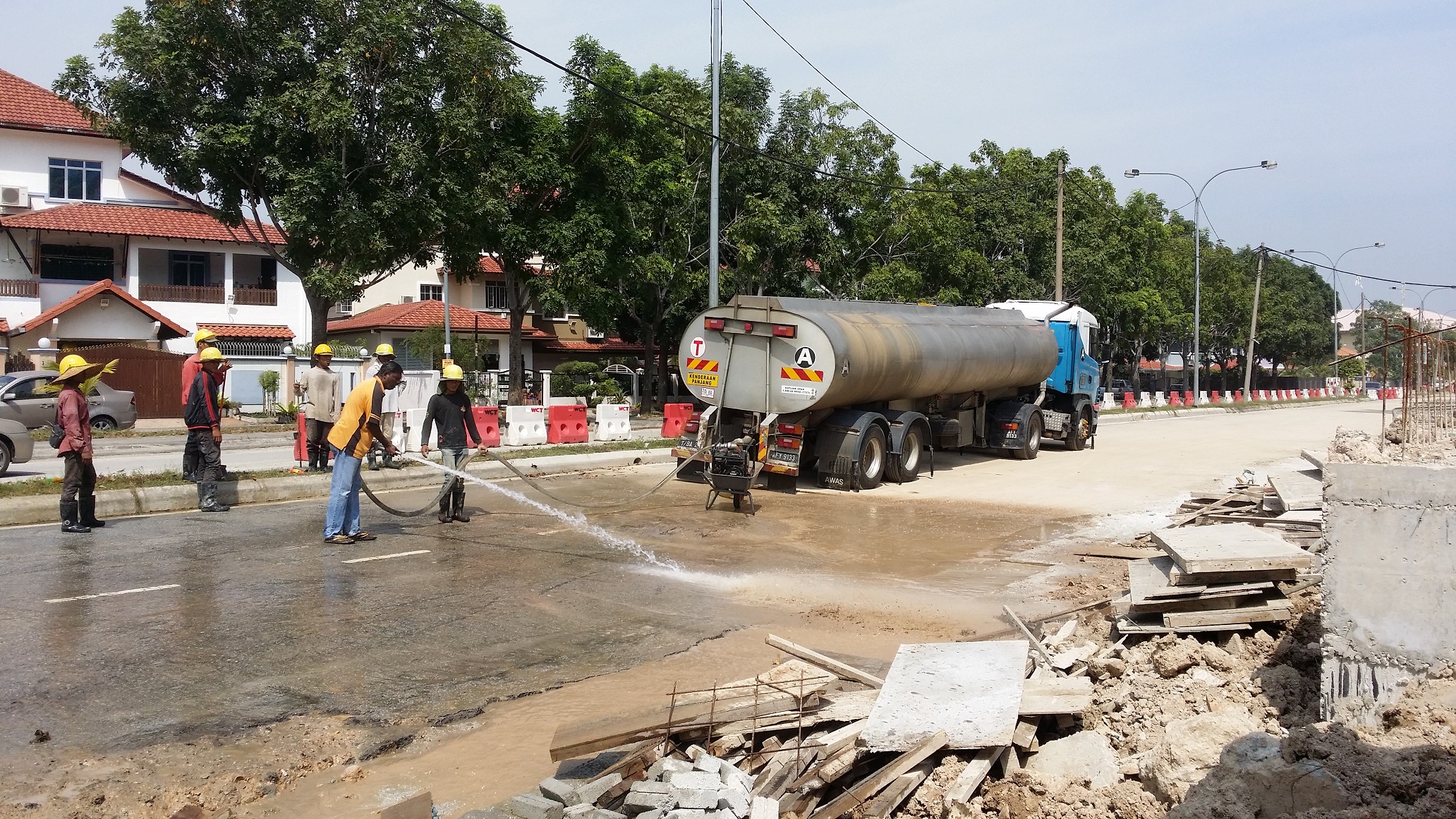 Krew pembinaan Asia memakai topi keselamatan beroperasi bersama lori tangki air Terasek