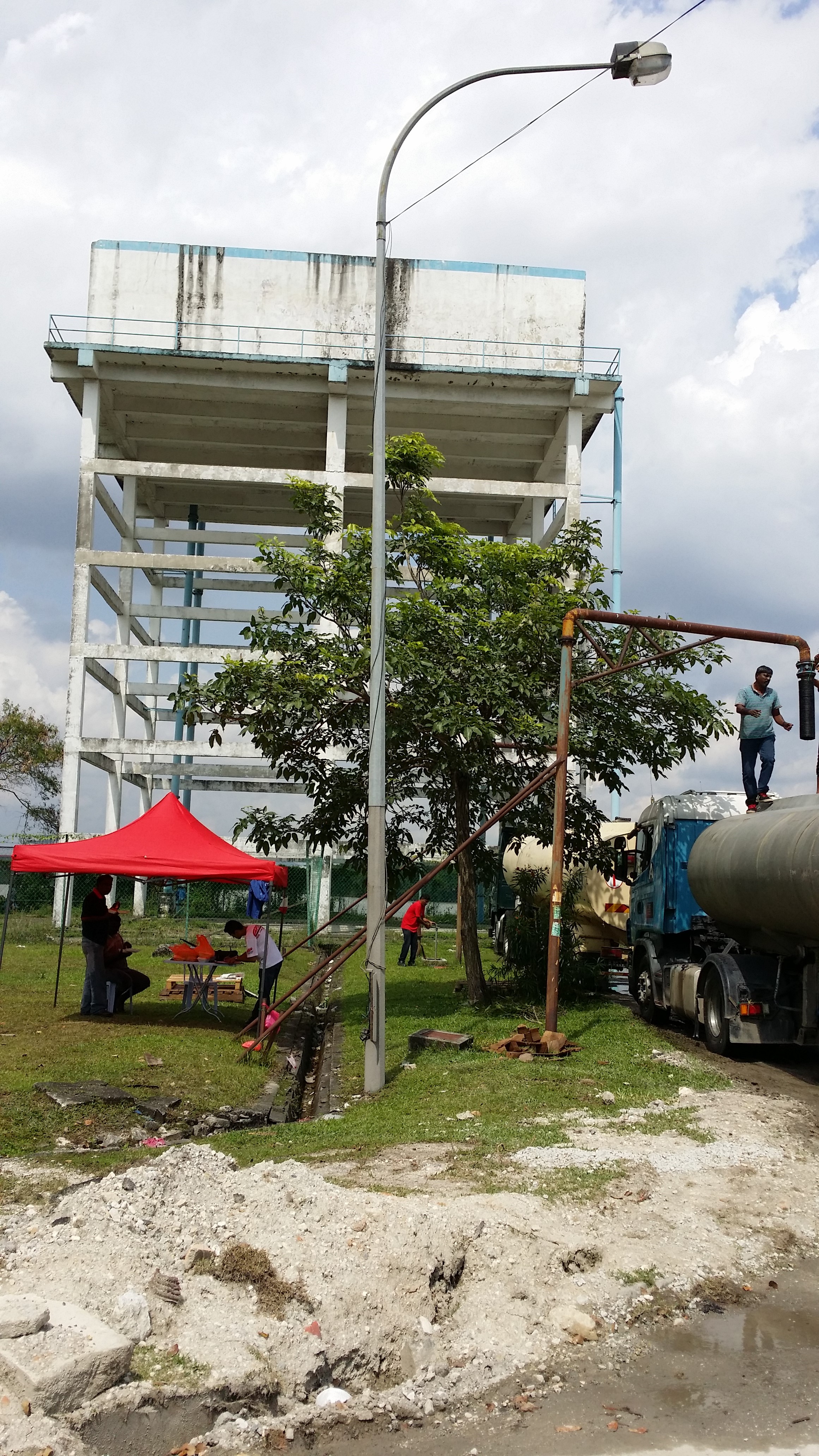 Lori tangki air mengisi air bersebelahan menara simpanan air